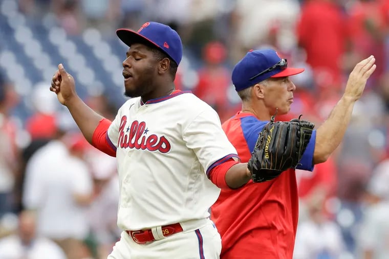 Phillies pitcher Hector Neris raises his arms, next to Manager Joe Girardi, after the Phillies beat the Marlins 7-4.  Neris got the save.