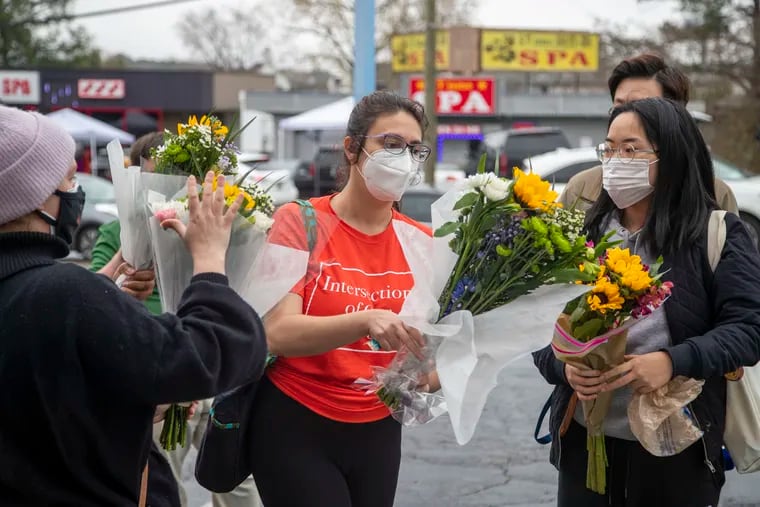 Roula AbiSamra, center, and Chelsey (last name withheld), right, prepare to lay flowers bouquets at a makeshift memorial outside of the Gold Spa near Atlanta Wednesday. Police in the Atlanta suburb of Gwinnett County say they've begun extra patrols in and around Asian businesses there following the shooting at three massage spas in the area that killed eight.