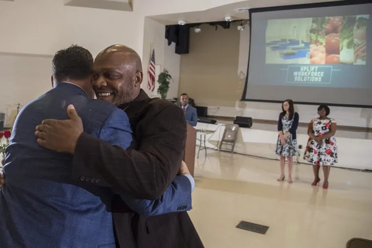 Daniel Garrison (right) hugs Jeff Brown, owner of Brown Super Stores, after speaking during graduation ceremonies  Enon Tabernacle Baptist Church. Twenty-two people, including Garrison, graduated from a six-week prison-to-productivity pathway that guaranteed them a job one of Brown’s ShopRite stores. CLEM MURRAY / Staff Photographer