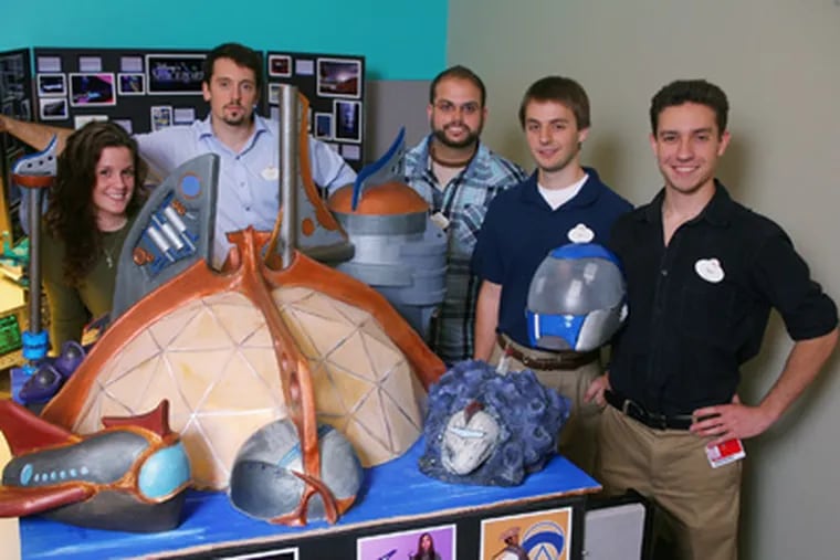 The Rowan-based team stands with its “Disney Spaceport” and mentor Daniel Joseph (center). The students are (from left) Elissa Hogan, David Lester, Raymond Scanlon, and Vincent Logozio. (Photo by Gary Krueger)