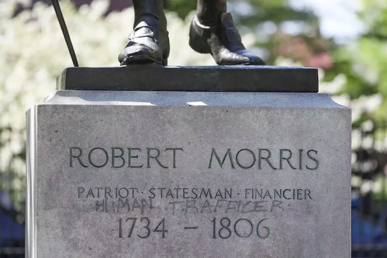 Vandalism on the base of the Robert Morris statue in Independence National Historic Park on Tuesday. Preservationists are having a difficult time removing it.