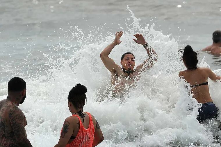 The waves were rolling in along the Ocean City beach as Ray Diaz, 24, from the Feltonville neighborhood of Philadelphia and his friend Isis (cq) Rodriguez, 20, from Juaniata, wade into the water on Labor Day 2014. (Clem Murray / Staff Photographer)