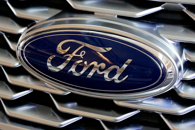 FILE- This Feb. 15, 2018, file photo shows a Ford logo on the grill of a car on display at the Pittsburgh Auto Show. Ford Motor Co. is repackaging a previously announced manufacturing investment in the Detroit area and now says it will spend $900 million and create 900 new jobs over the next four years. Most of the new workers will build a new generation of electric vehicle at Ford’s existing factory in Flat Rock, Michigan, south of Detroit, which will see an $850 million investment.