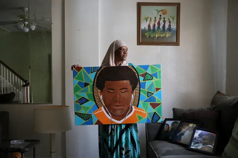 Jackee Nichols holding a painting of her grandson, Rasul Benson, in her South Philadelphia home. Benson was 15 when he was shot and killed at a gas station at 25th Street and Passyunk Avenue in October 2018.