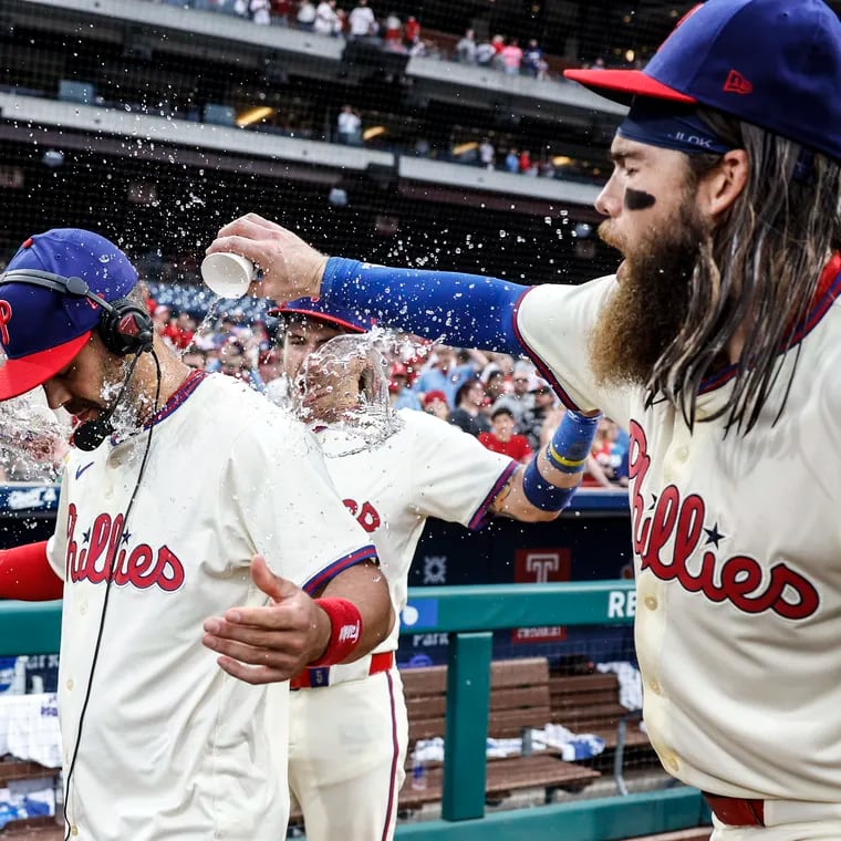 Phillies Whit Merrifield gets a water bath from teammates Bryson Stott behind and Brandon Marsh at right after sweeping the series with the Giants at Citizens Bank Park in Philadelphia, Monday, May 6, 2024 Phillies beat  the Giants 6-1.