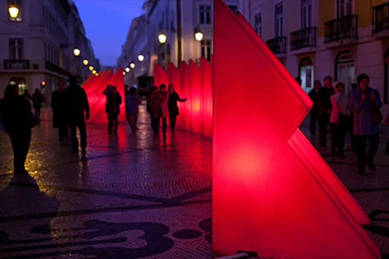 Pedestrians walk around Christmas decorations in Lisbon's main shopping street. Usually, the streets are brightly decorated, but Portugal and other European countries are slowing their holiday spending. (Armando Franca / Associated Press)