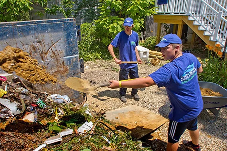 Student volunteers (right) Ryan Koch, 15, and Elijah Keliwitz, 16, both of Gilead, Nb., shovel dirt and debris into a dumpster at a home damaged by Hurricane Sandy on Cedar Berry Land, Toms River, July 23, 2014.  ( DAVID M WARREN / Staff Photographer )