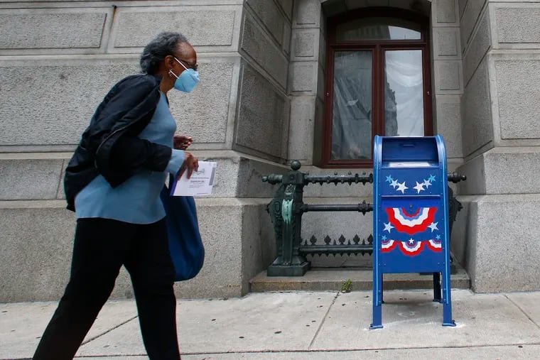 A voter walks with their ballot to a ballot drop box at the south portal of City Hall on Thursday, May 28, 2020.