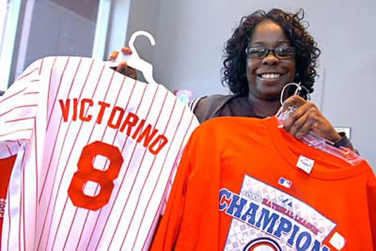 Cavetta Nesmith, 40, of West Oak Lane shows the merchandise she's buying today from the Majestic Clubhouse at Citizens Bank Park. Nesmith said she prays before every game. (Sarah J. Glover / Staff Photographer)