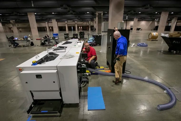 Workers install equipment for processing mail ballots at the Pennsylvania Convention Center in Philadelphia on Sept. 17. Elections officials in the city and elsewhere have spent millions on sophisticated equipment for processing, sorting, opening, and counting mail ballots, in an effort to avoid a long wait before results in the 2020 presidential election are known.