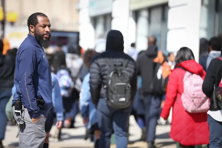 Security officer Rogelio Burton, left, watches as students leave school at the end of the day from Mathematics Civics and Sciences Charter School in Philadelphia. The school does not use metal detectors.