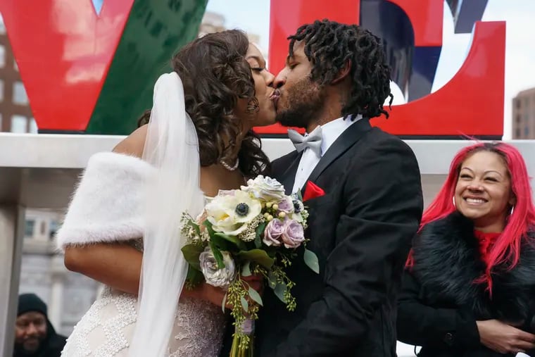 Deanna Earland Gray (left) and Monroe Gray kiss after exchanging vows at their wedding in Love Park on Valentine's Day Friday.