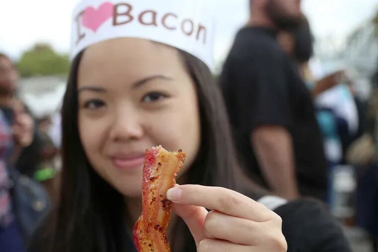 Parim Sukosi holds up maple-candied bacon at the Pennsylvania Bacon Festival at Xfinity Live!