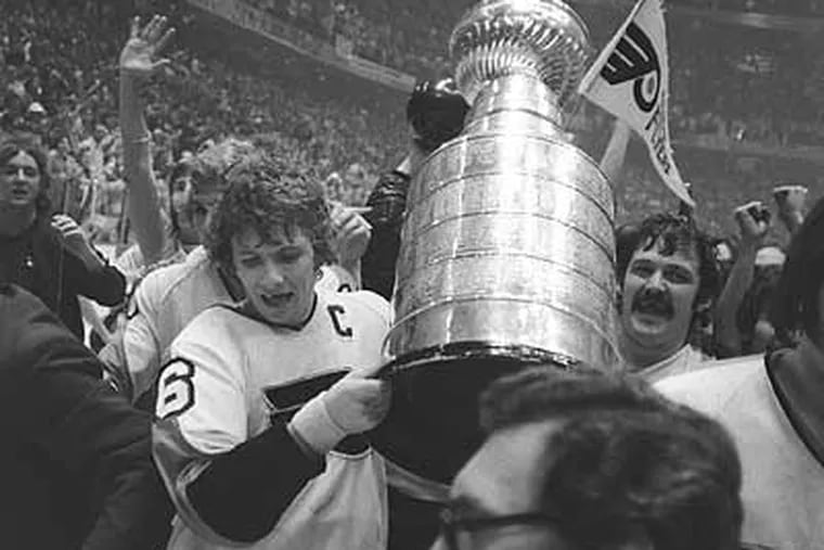 Flyers captain Bobby Clarke, left, and goalie Bernie Parent carry the Stanley Cup amidst their ecstatic fans in the Spectrum after defeating the Boston Bruins in the 1974 Stanley Cup finals.
