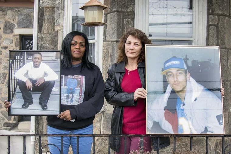 Yullio Robbins (left), and Sophia Fleming (right), hold up photos of their sons on the porch of Fleming&#039;s home in Germantown in Philadelphia. Their sons&#039; unsolved murders are an example of the dreaded Philly Shrug.