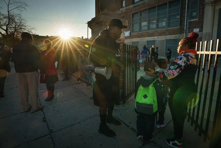 Antoine Little, center, an advocate and parent of three children at Thomas M. Peirce Elementary, talks with a parent prior to the start of a protest outside the school. He is organizing parents to demand answers about asbestos at Peirce at 23rd and Cambria.