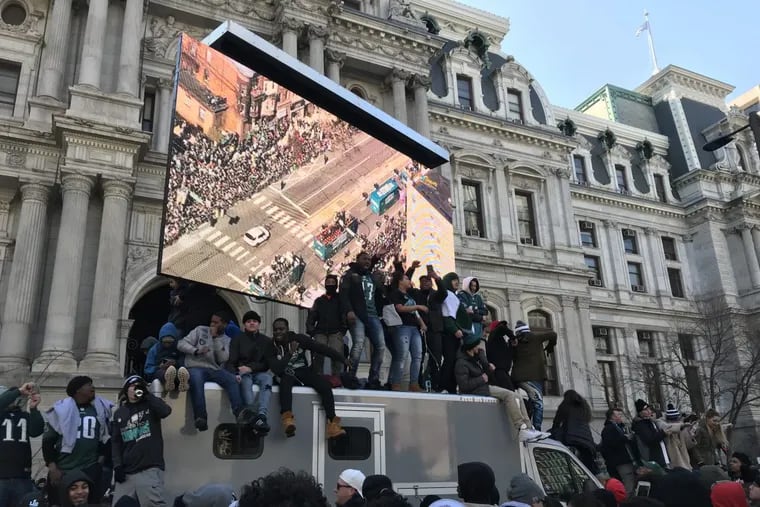 Fans stand on a truck carrying a jumbotron outside City Hall during the Eagles Super Bowl parade.