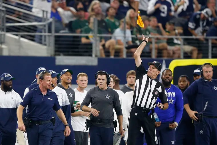 Side judge Scott Edwards (3) throws a penalty flag after Cowboys head coach Jason Garrett (left) threw a challenge flag during a game against the Packers earlier this month.