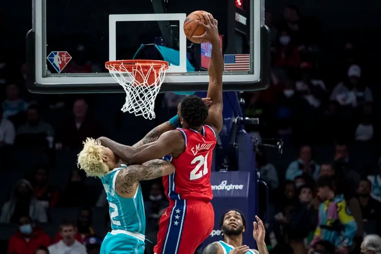 Sixers center Joel Embiid is fouled while attempting to dunk over the Hornets' Kelly Oubre Jr. (12) during the first half Wednesday