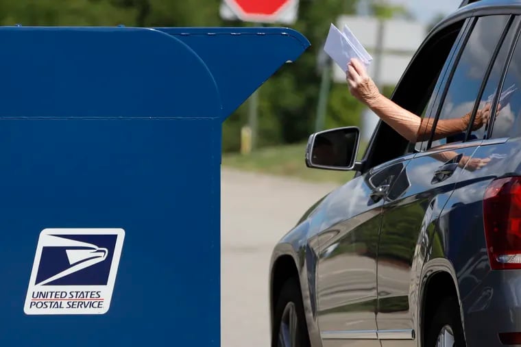 A person deposits mail in a box outside United States Post Office in Cranberry Township, Pa.