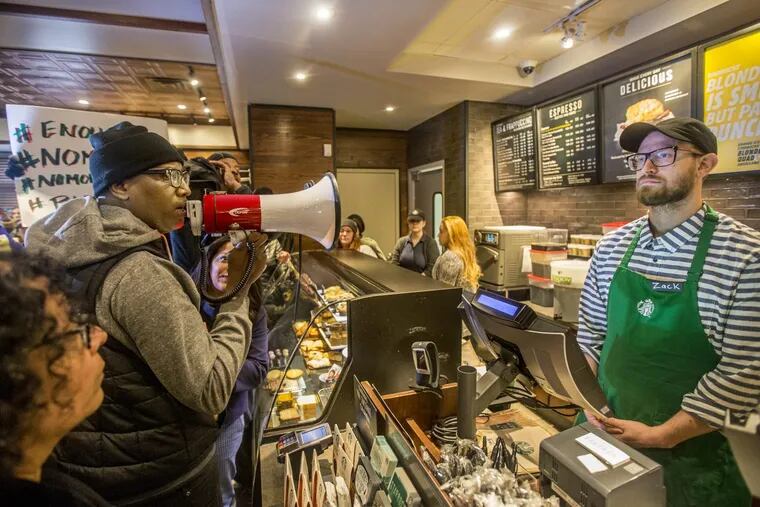Local Black Lives Matter activist Asa Khalif, left, stands inside the Starbucks at 18th and Spruce, and over a bullhorn, demands the firing of the manager.