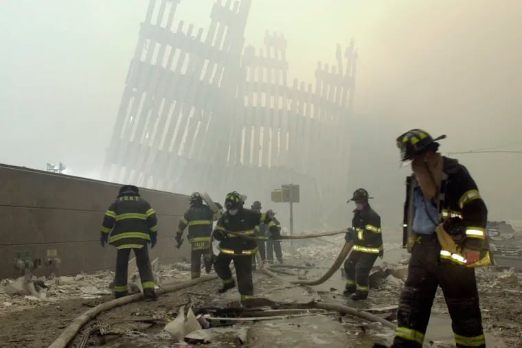 In this Sept. 11, 2001 file photo, with the skeleton of the World Trade Center twin towers in the background, New York City firefighters work amid debris on Cortlandt St. after the terrorist attacks.