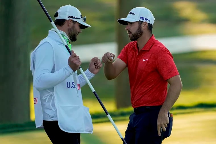 Matthew Wolff (right) bumps fists with his caddie after taking the lead.