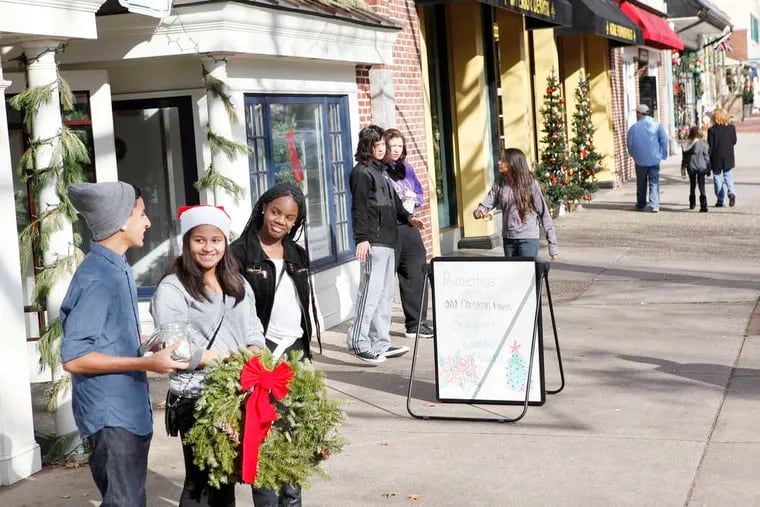 From left, Johnathan Cabrera, 16; Siarah Freeland, 15; and Jada Cordero, 14, encourage passers-by to buy a wreath or make a donation. L.U.C.Y. sells its holiday wreaths from a vacant store on East Kings Highway.
