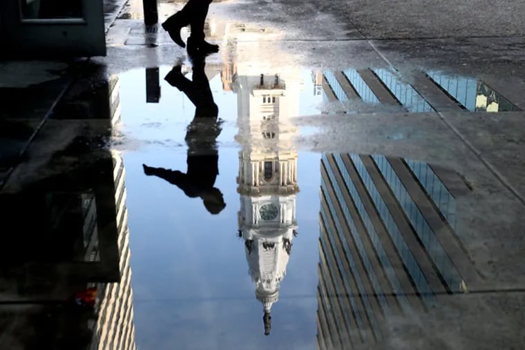 City Hall is reflected in a puddle of melted snow - along with a pedestrian trying to avoid the water.