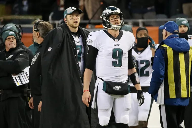 Eagles quarterback Nick Foles (9) and backup quarterback Nate Sudfeld (7) look up at a replay of an interception Foles threw in the second quarter of the Wild Card game against the Chicago Bears.