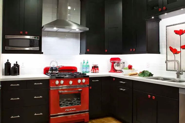 A 14-by-12 foot Atlanta kitchen designed by Kandrac & Kole Interior Designs features black cabinets with red hand-blown glass knobs, a retro red stove from Big Chill, a red mixer and, this being Atlanta, Coca-Cola.  Illustrates DESIGN-KITCHENS (category l), by Jura Koncius, (c) 2014, The Washington Post. Moved Thursday, October 30, 2014. (MUST CREDIT: Jill Buckner Photography.)