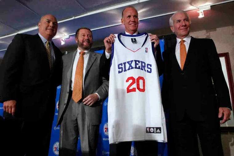Sixers coach Doug Collins holds a jersey with his old number while flanked by (from left) team general manager Ed Stefanski, Comcast-Spectacor president Peter Luukko, and company chairman Ed Snider. Comcast-Spectacor has owned the Sixers since 1996.