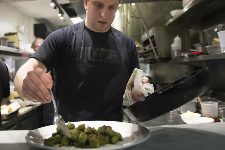 Chef Yehuda Sichel spoons some bitter-greens gnocchi onto a plate for serving at Abe Fisher in Center City.