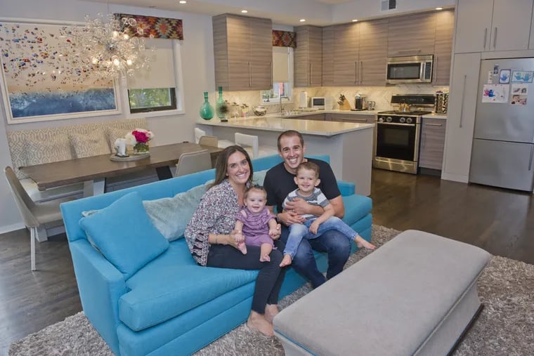Paige and Ray Jaffe with their daughter Noa, 8 months, and son Max, 2, in their open living room, kitchen, dining room of their Fitler Square/Rittenhouse area townhouse. When they remodeled, they picked a teal sofa to add color amid their neutral decor.