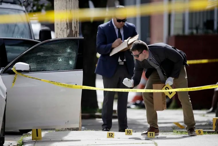 Detectives investigate a triple shooting on Kershaw Street in West Philadelphia on Sunday.