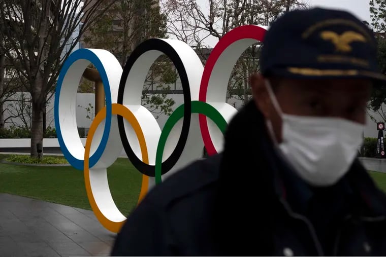 A security guard walks past the Olympic rings near the New National Stadium in Tokyo.