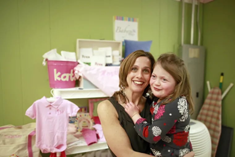 Colleen Mook, founder of Baby Be Hip, specializing in personalized gifts for newborns, holds 6-year-old Ellie. (David Swanson / Staff Photographer)