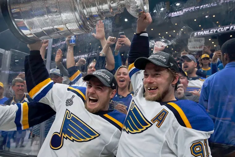St. Louis Blues' Ivan Barbashev, left, and Vladimir Tarasenko hold the Stanley Cup as fans in the stands celebrate after the Blues defeated the Boston Bruins in Game 7 on Wednesday in Boston.