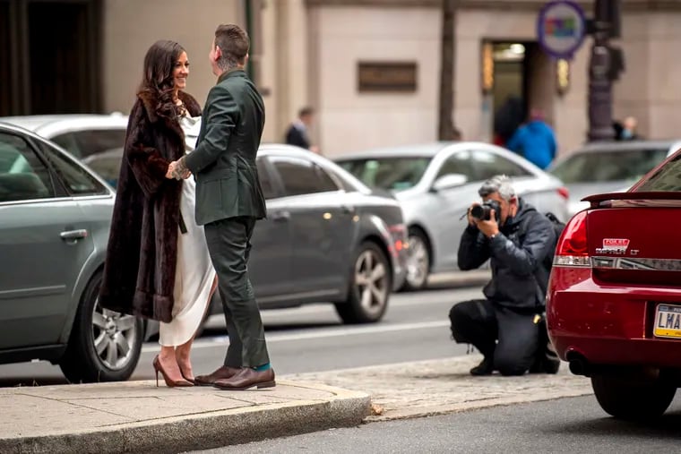 December 6, 2021: In the middle of a busy South Broad Street, photographer Eddy Marenco captures newlyweds Olivia and Jimmy Jakubik - with a view of City Hall in the background - shortly after they were married there earlier in the afternoon.