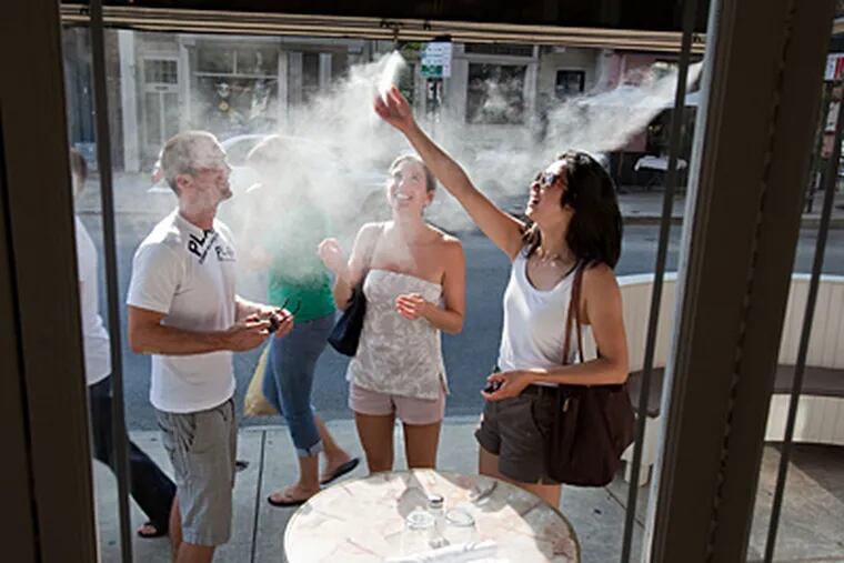 Passerbys (left to right) Roman Graber of Copenhagen, Yvonne Baker of
Philadelphia and Tiffany Ng of Copenhagen and San Francisco enjoy the
cooling mist from the awnings at Twenty Manning Grill on Aug. 4. (David M Warren / Staff)