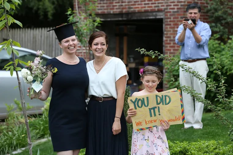 Stephanie Pierson, 48, (left) and her daughter, Arielle, 28, (center) who graduated summa cum laude from the University of Pennsylvania, were surprised by family and friends outside their home in Collingswood, N.J. on May 17, 2020. They did a drive-by graduation celebration for them. Standing with them is Stephanie’s daughter, Eliana, 10, and husband, Pedro Vadillo (right) take a photo.