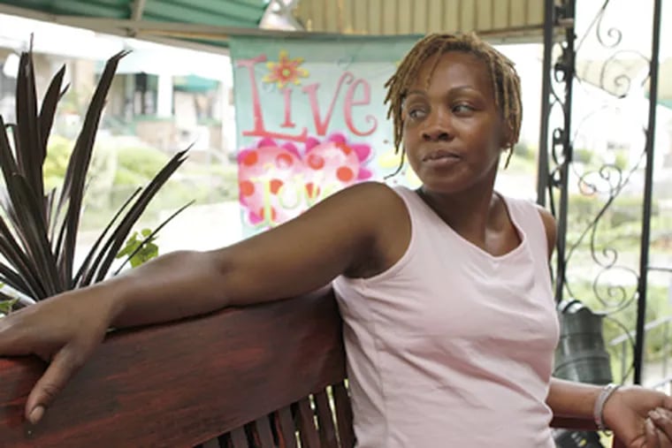 Sharletta Ambey on the front porch of her house, now scarred by bullet holes. (Michael S. Wirtz / Staff Photographer)