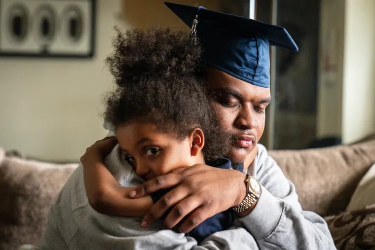 Dashawn Walker, who was shot 10 times in February, hugs his 5-year-old brother, Jayden Brockington, while trying on his graduation cap at his home in Philadelphia.