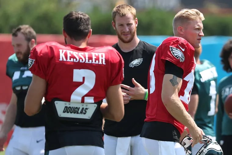 Eagles quarterbacks Cody Kessler,  Carson Wentz, and Josh McCown  (right) gather on the field before a joint practice with the Baltimore Ravens on Monday.