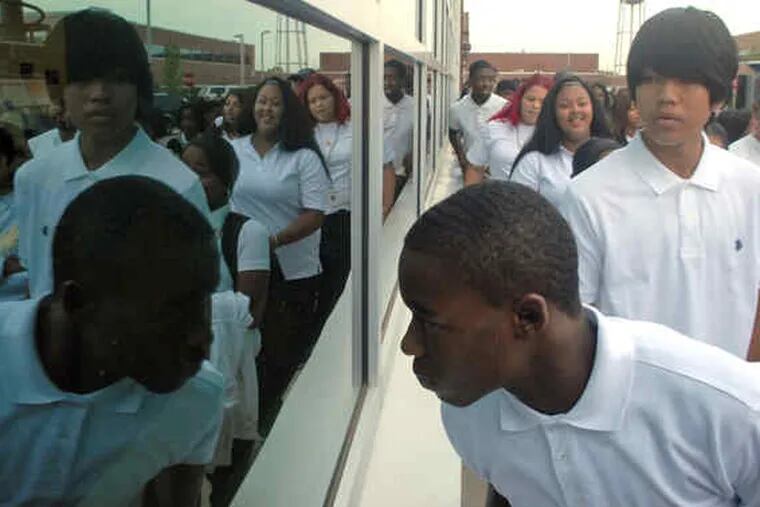 At the new Fels High School in Northeast Philadelphia, freshman Marcus Pittman , 13, takes a peek inside as he arrives with classmates for the first day of school. The day started with proud speeches, as well as a rap from Mayor Nutter: &quot;Come to school, don't be a fool.&quot;