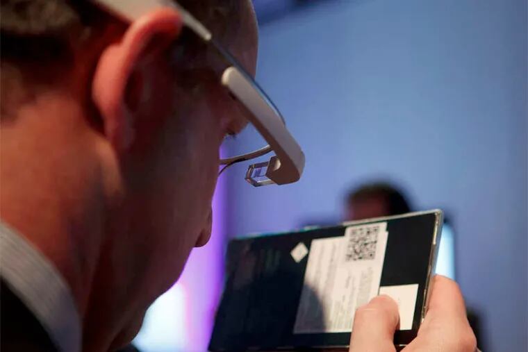 At a tech convention this year, an employee, left, shows how Google Glass- connected glasses can read barcodes.
