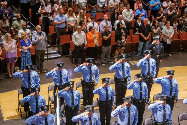 Philadelphia police academy graduates salute during National Anthem at the start of a graduation ceremony in August. The department and the police union are asking state officials to relax reading and fitness requirements.