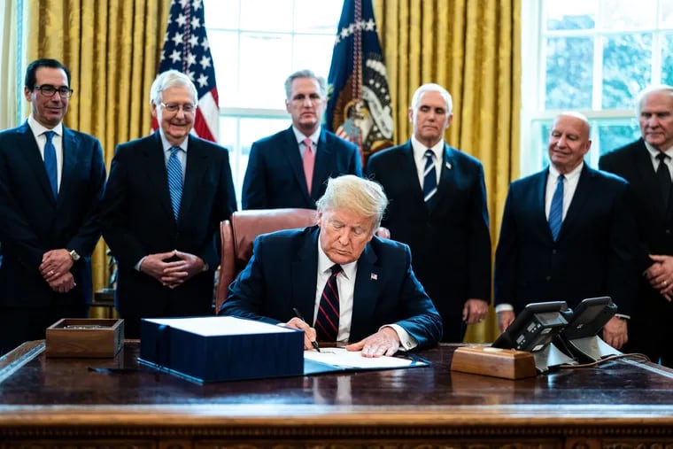 U.S. President Donald Trump signs HR 748, the CARES Act, in the Oval Office of the White House on March 27, 2020, in Washington, D.C.