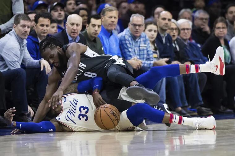 The Sixers’ Robert Covington (33) and the Nets’ DeMarre Carroll battle for the ball during the first half.