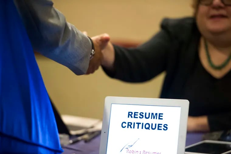 FILE photo shows a job seeker at a table offering resume critiques during a 2016 job fair.